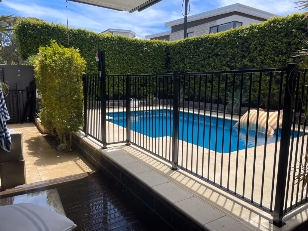 Black aluminium tubular fencing surrounding a pool