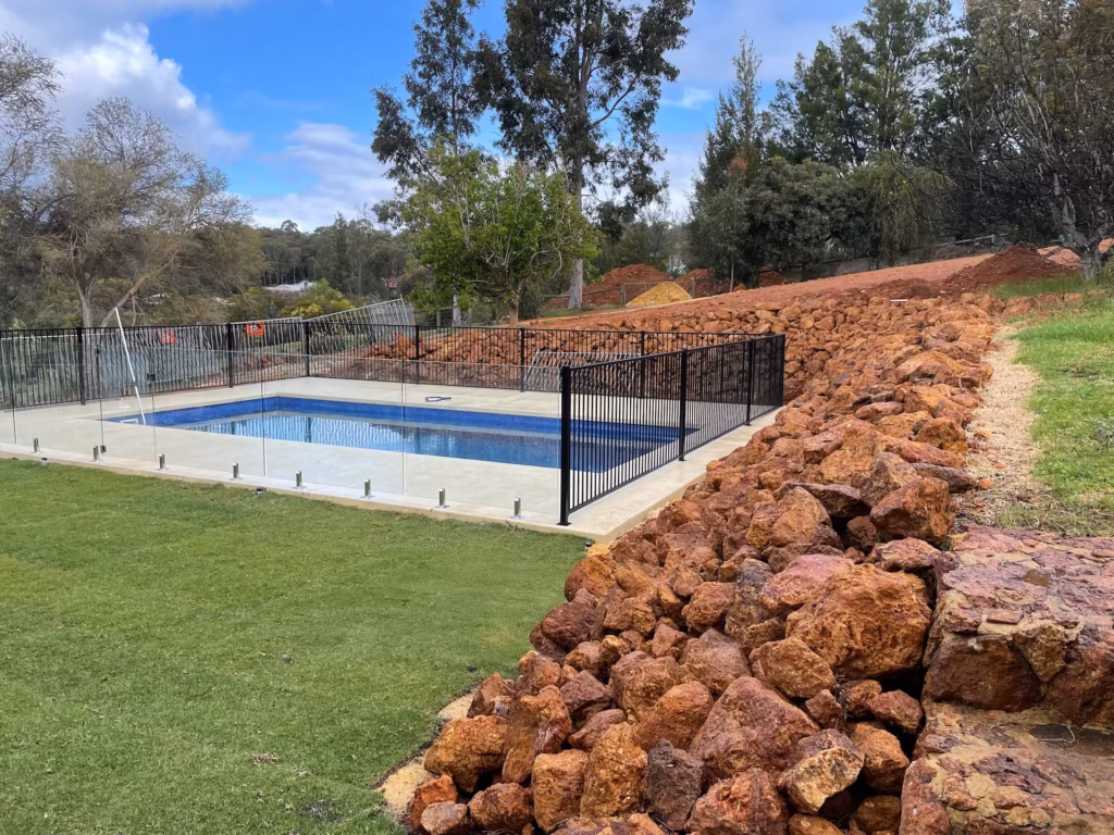 Pool fence with a combination of black tubular aluminium fencing around 3 sides and frameless glass fencing around the last side