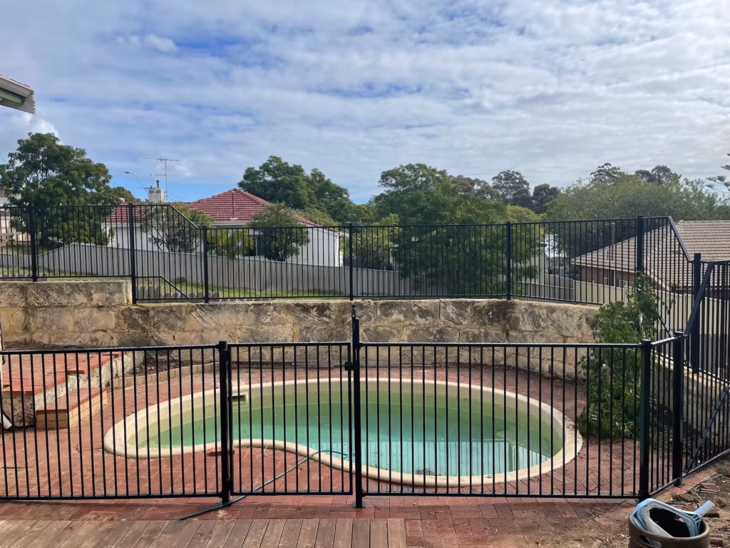 A circular pool surrounded by tubular aluminium fencing
