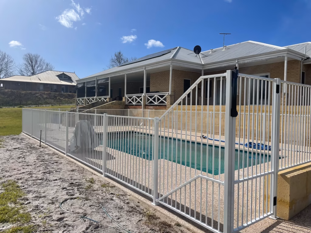 A white aluminium tubular fence surrounding a rectangular pool