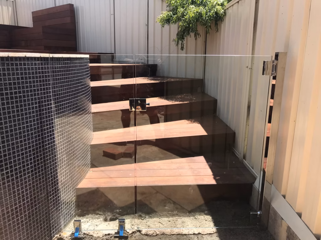 Frameless glass gate in front of a wooden outdoor staircase