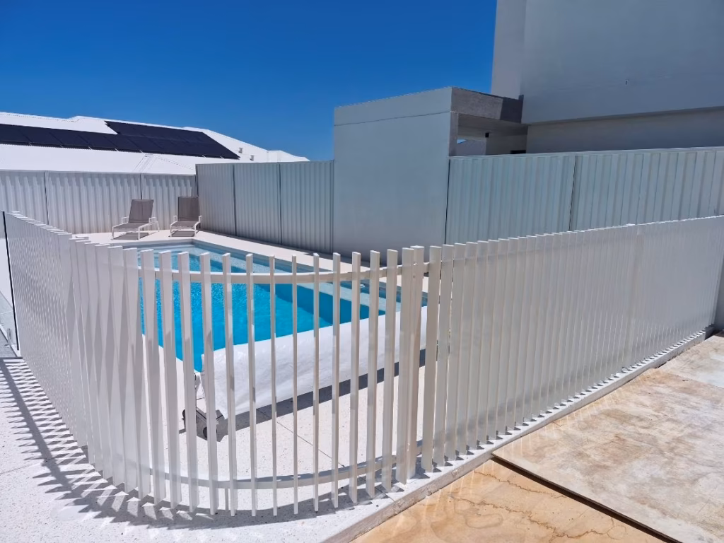 curved white blade fence around a clear blue pool